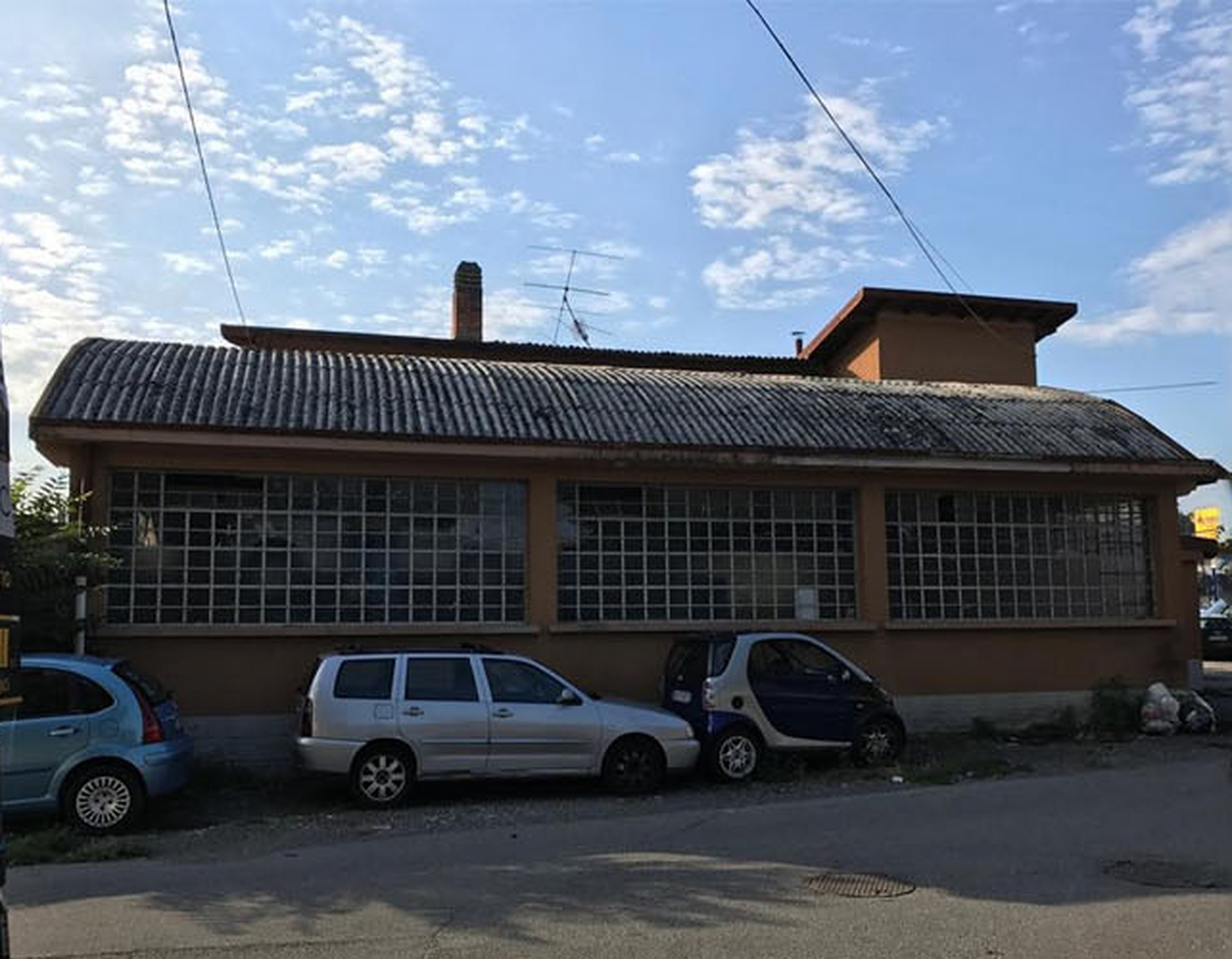 Capannone con copertura curva in lastre ondulate grigie di cemento amianto, prima della rimozione