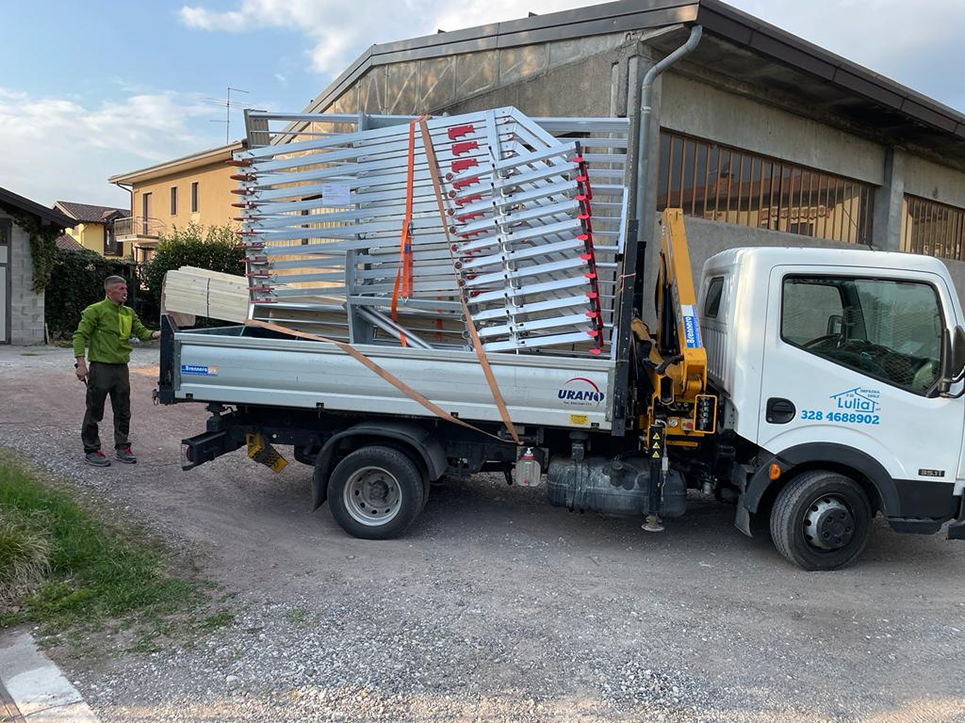 Autocarro con gru carico di parapetti RSS in alluminio, fissati con cinghie e pronti per il cantiere